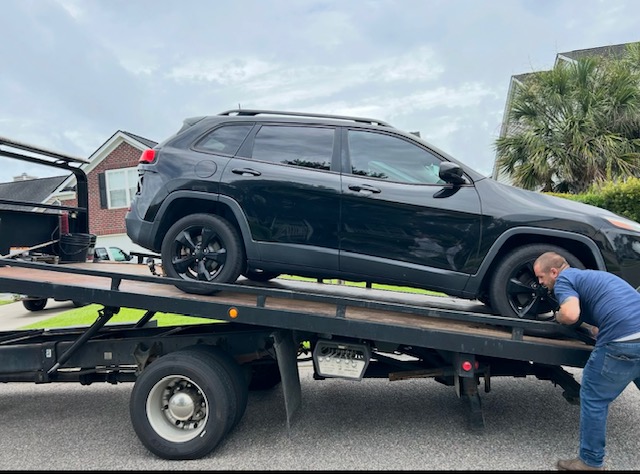 Loading a black SUV onto the flatbed in a neighbourhood street