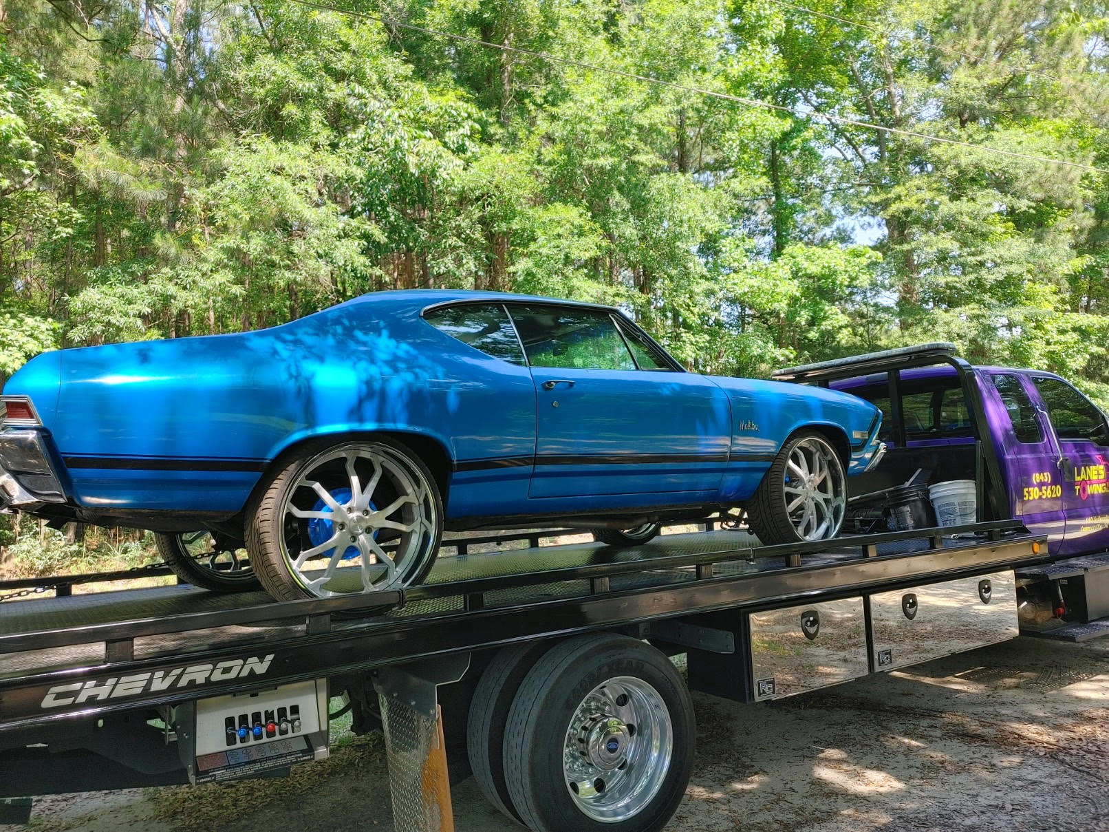 A blue classic car riding on the Lane's Towing flatbed