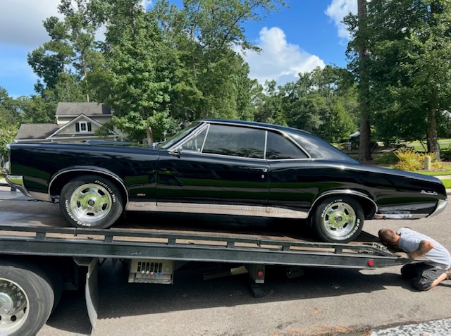 A black classic muscle car strapped down on the flatbed